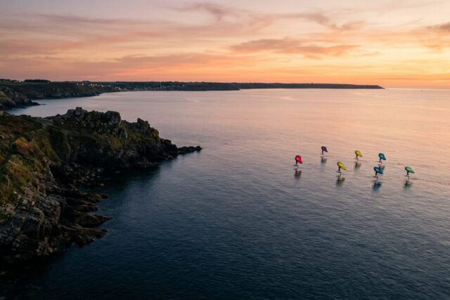Plusieurs wingfoilers naviguant dans une baie profonde au crépuscule